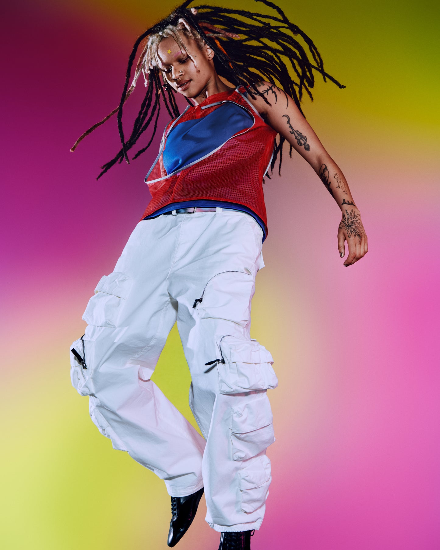 A young person with white and black hair wears a classic yellow Hydro-Star® pimple patch from Starface on their forehead while jumping.