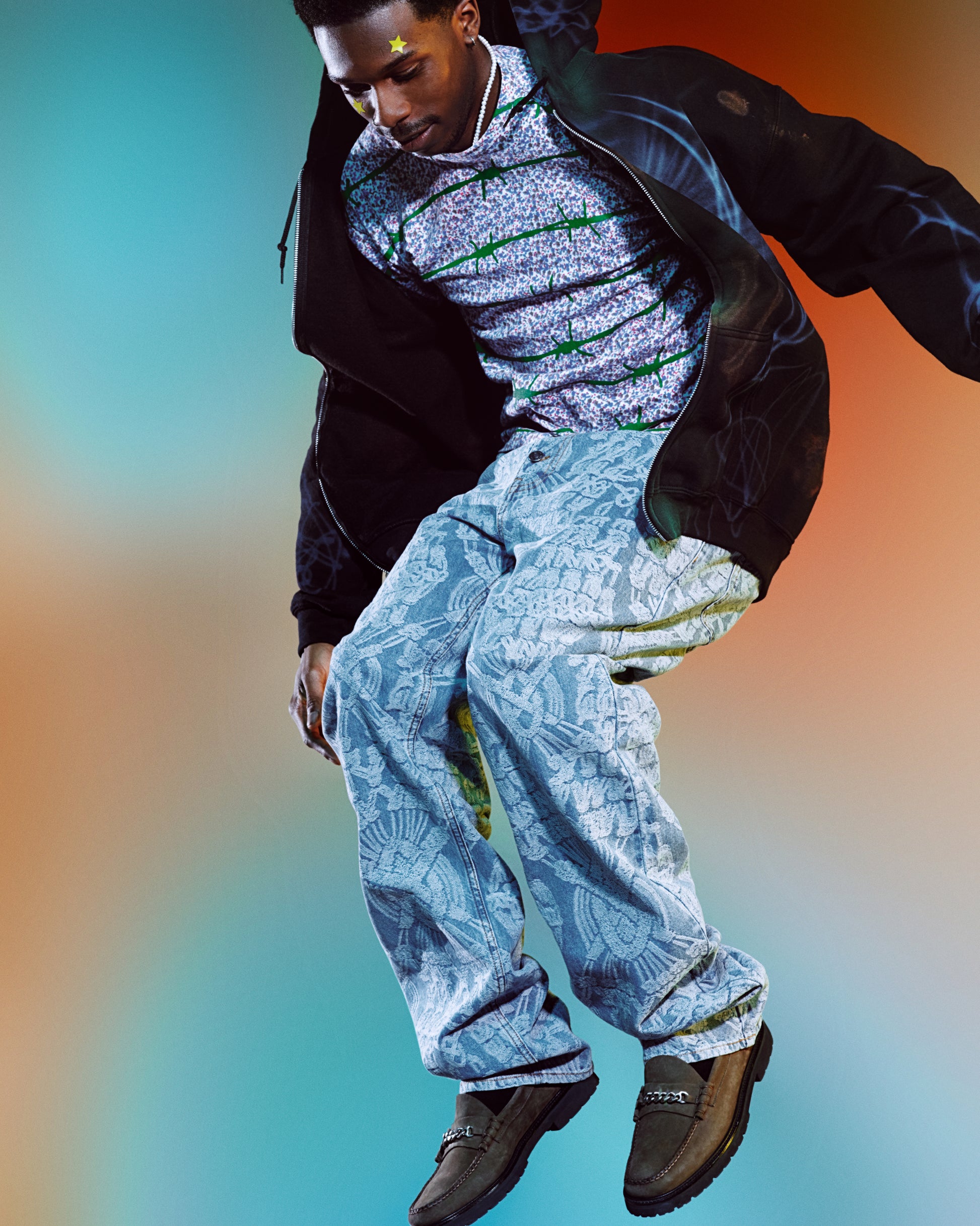 A young person with a mustache jumping wears a yellow XL Big Star hydrocolloid pimple patch on their forehead and cheek.