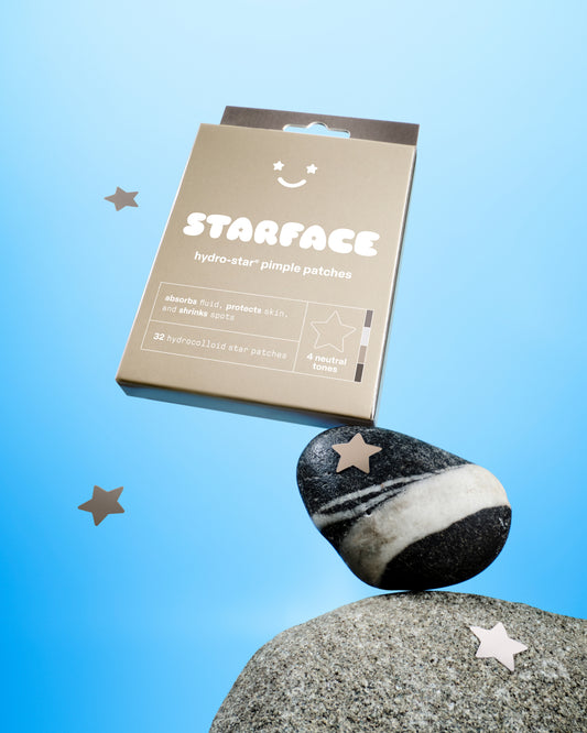 Earth Star box balances on top of a striped black and white rock. Two neutral hydrocolloid stars float in the foreground. Two stars are stuck to rocks.