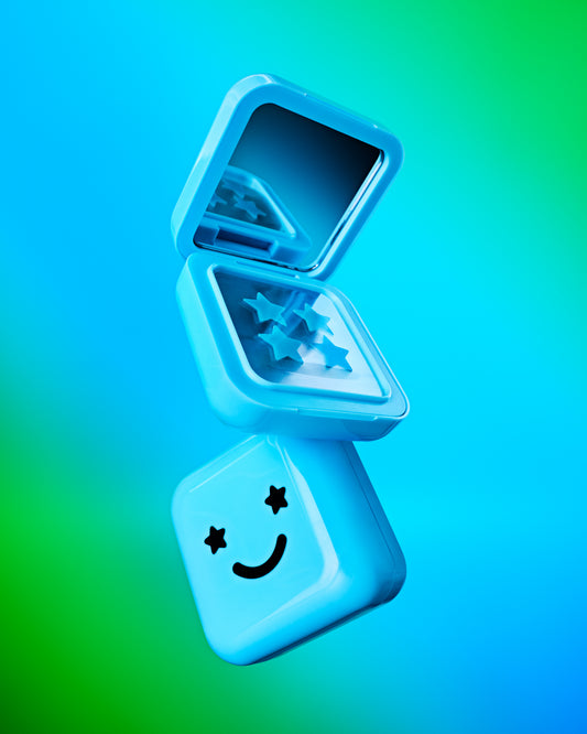 An open travel-friendly Hydro-Star® + Big Blue compact case with a black smiley face is stacked on top of another compact case.